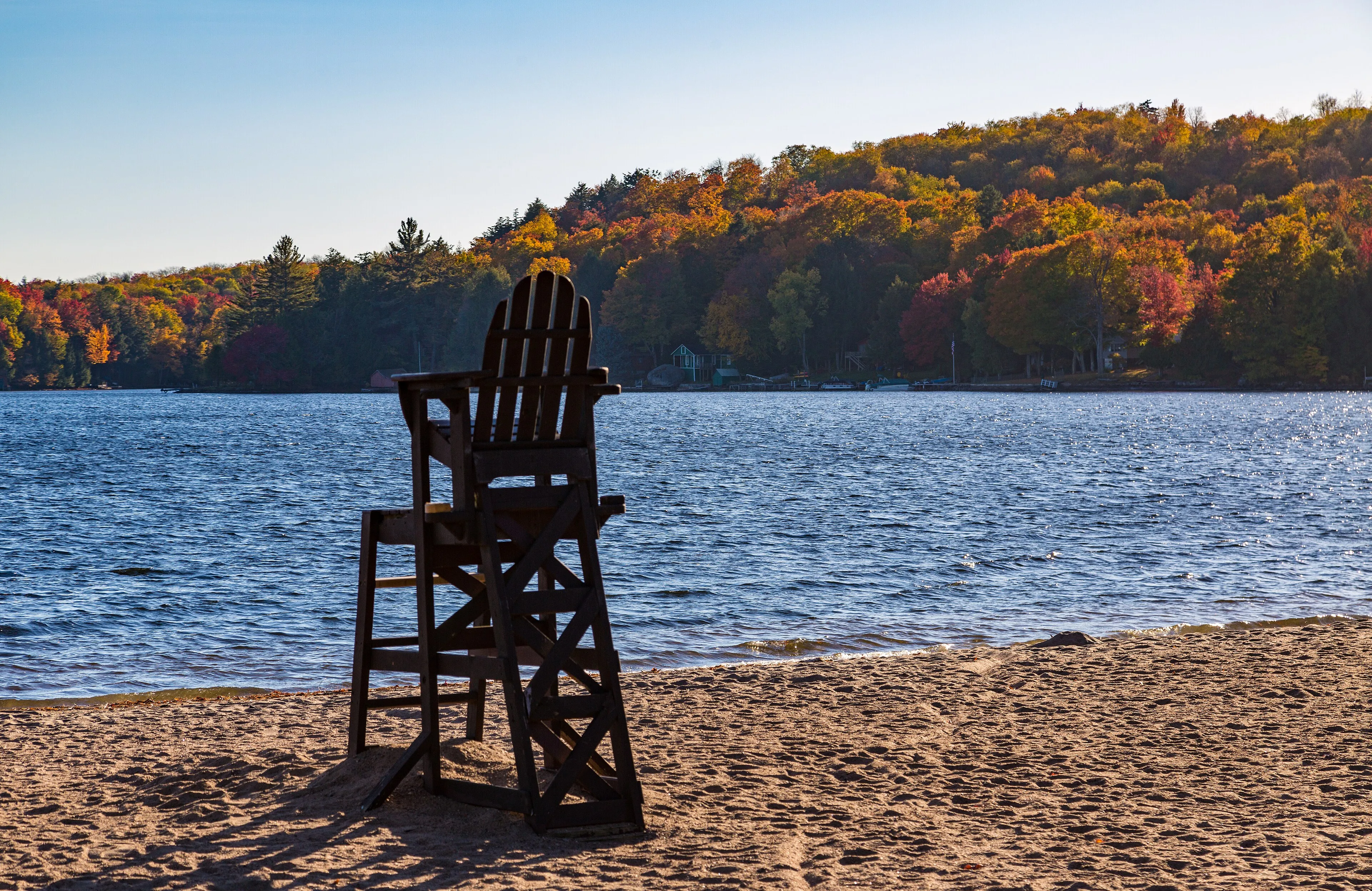 The Cranberry Lake shoreline in autumn, with red and gold trees reflected in still water.